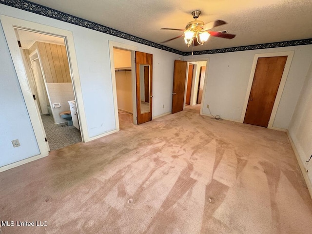 unfurnished bedroom with connected bathroom, a textured ceiling, and carpet flooring