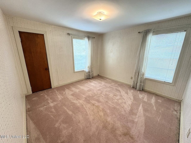 empty room with baseboards, light colored carpet, and wallpapered walls