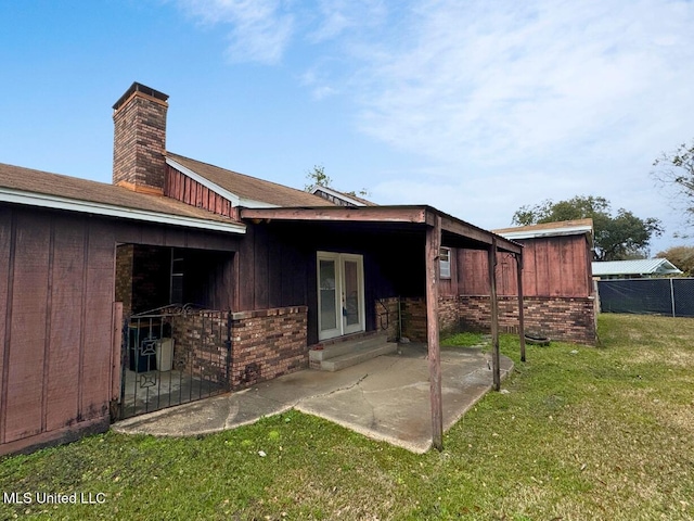 back of house with a patio area, a chimney, board and batten siding, and brick siding