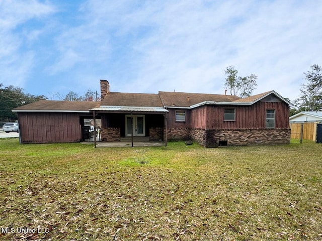 back of property with a yard, a chimney, fence, and a patio