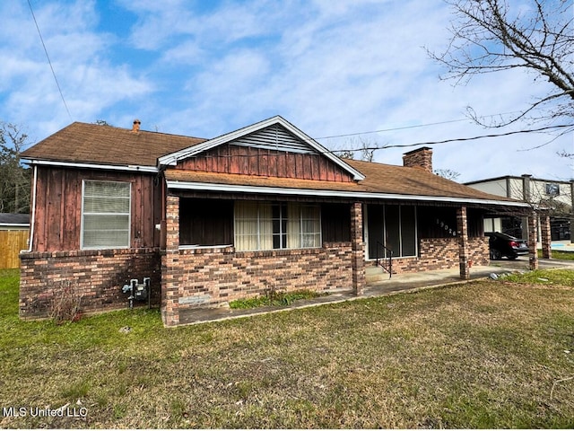 view of front of property featuring a chimney, a front lawn, and brick siding