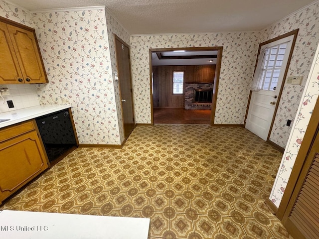 kitchen with black dishwasher, a fireplace, baseboards, and wallpapered walls