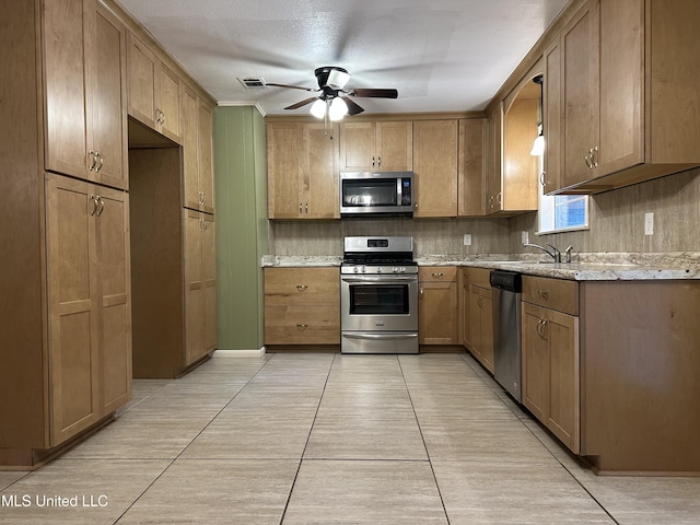 kitchen with appliances with stainless steel finishes, a textured ceiling, ceiling fan, sink, and light tile patterned floors