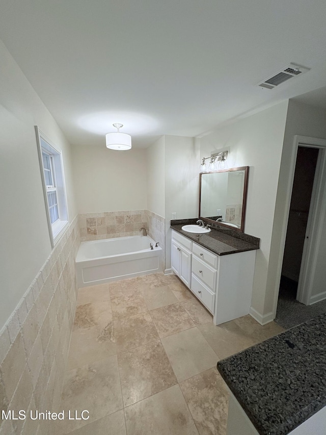 full bath featuring tile patterned flooring, visible vents, a garden tub, and vanity