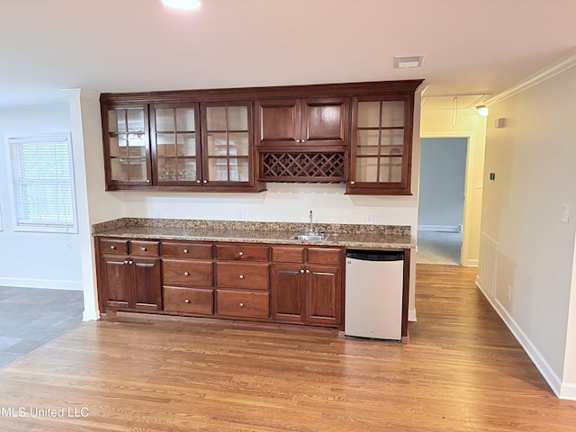 bar featuring crown molding, a sink, baseboards, light wood-type flooring, and refrigerator