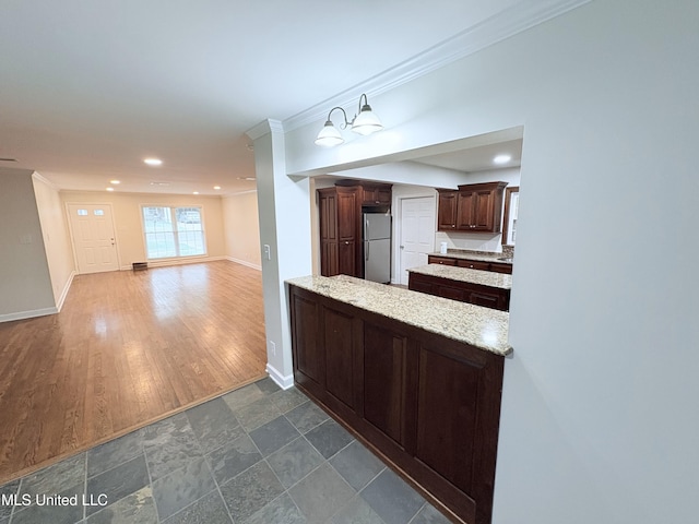 kitchen featuring dark brown cabinetry, pendant lighting, baseboards, freestanding refrigerator, and ornamental molding