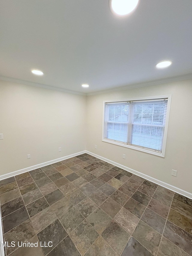 spare room featuring crown molding, baseboards, and stone finish floor
