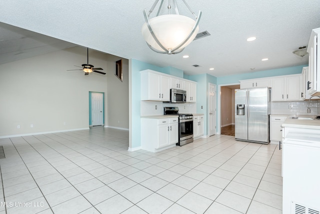 kitchen featuring white cabinets, light tile patterned floors, appliances with stainless steel finishes, ceiling fan, and vaulted ceiling