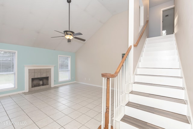 staircase featuring tile patterned floors, high vaulted ceiling, a tile fireplace, and ceiling fan