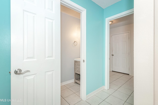 corridor featuring a textured ceiling and light tile patterned floors