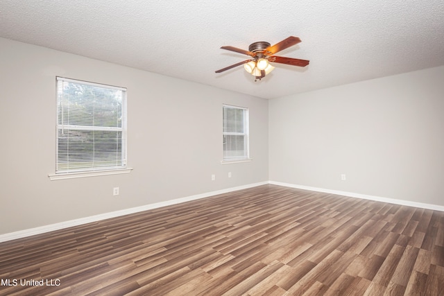 empty room with a textured ceiling, a healthy amount of sunlight, and dark wood-type flooring