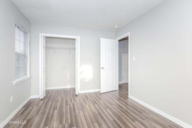 unfurnished bedroom featuring light hardwood / wood-style flooring, a textured ceiling, and a closet