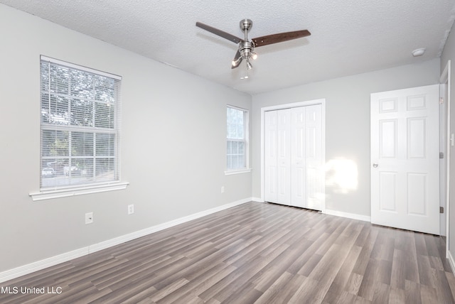 unfurnished bedroom featuring a textured ceiling, dark hardwood / wood-style floors, a closet, and ceiling fan