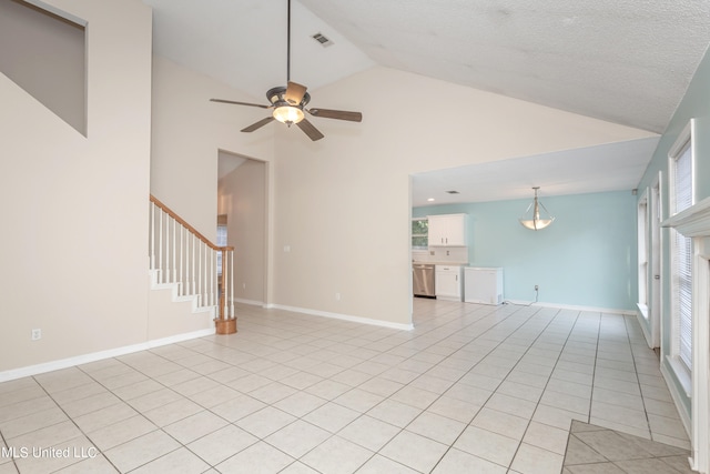 empty room with light tile patterned floors, high vaulted ceiling, a wealth of natural light, and ceiling fan with notable chandelier