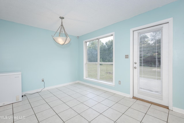 unfurnished dining area with a textured ceiling and light tile patterned flooring