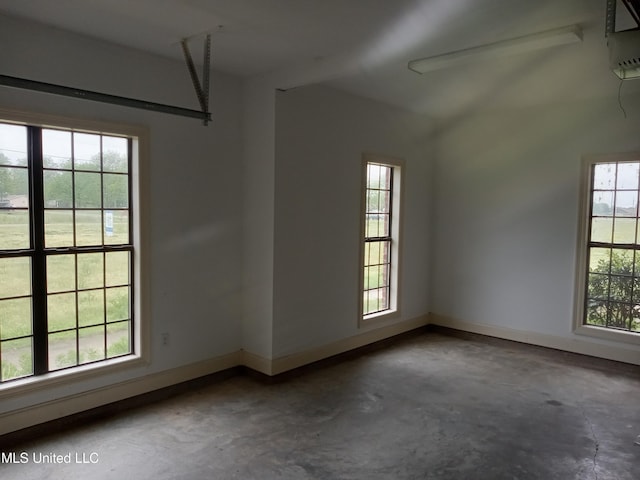 38 3rd St, Cleveland, MS 38732 - spare room with baseboards, a wall mounted air conditioner, lofted ceiling, and unfinished concrete floors