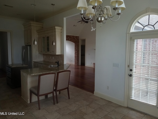 38 3rd St, Cleveland, MS 38732 - kitchen with a breakfast bar area, fridge, light stone counters, a peninsula, and glass insert cabinets