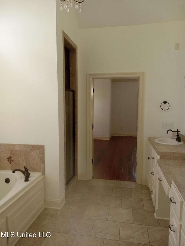 38 3rd St, Cleveland, MS 38732 - bathroom featuring a notable chandelier, vanity, baseboards, a shower stall, and a bath