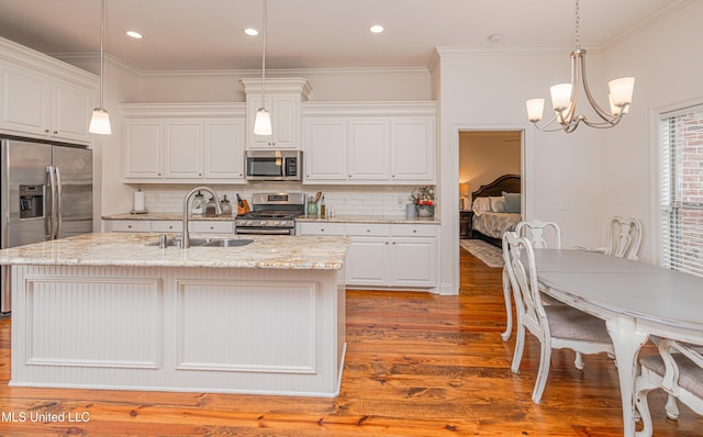 228 Falls Xing, Madison, MS 39110 - kitchen featuring appliances with stainless steel finishes, a sink, wood finished floors, a chandelier, and backsplash