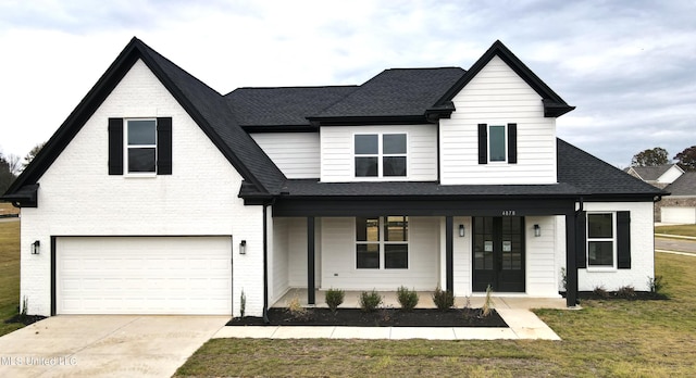 view of front of property with a porch, a front lawn, and a garage