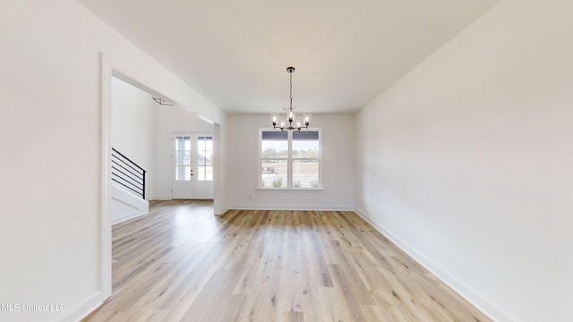 unfurnished dining area featuring french doors, light hardwood / wood-style floors, and a notable chandelier