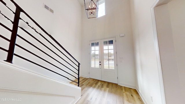 entryway featuring a towering ceiling, french doors, and light hardwood / wood-style floors