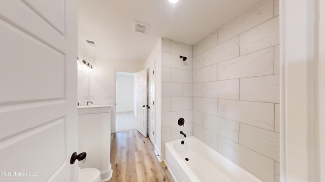 full bathroom featuring toilet, tiled shower / bath, hardwood / wood-style floors, and vanity