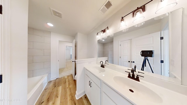 bathroom with vanity, hardwood / wood-style floors, and a bathing tub