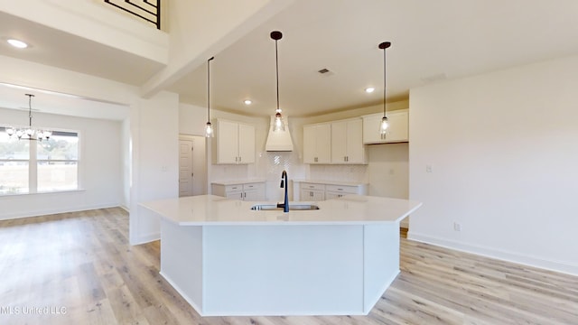 kitchen featuring light hardwood / wood-style flooring, white cabinetry, a kitchen island with sink, and sink