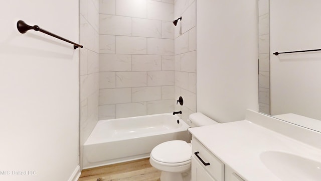 full bathroom featuring tiled shower / bath, vanity, hardwood / wood-style flooring, and toilet