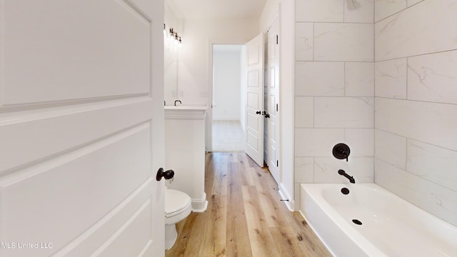 full bathroom with toilet, tiled shower / bath, hardwood / wood-style floors, and vanity