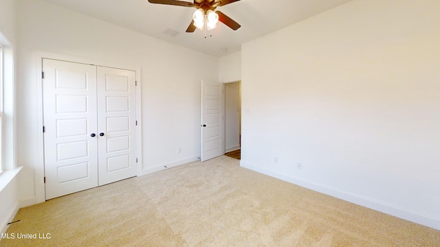 unfurnished bedroom with a closet, light colored carpet, and ceiling fan