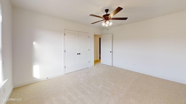 unfurnished bedroom with light colored carpet, a closet, and ceiling fan