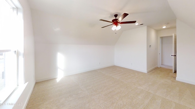 additional living space with vaulted ceiling, light colored carpet, and ceiling fan