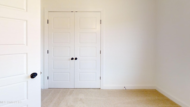 unfurnished bedroom with a closet and light colored carpet