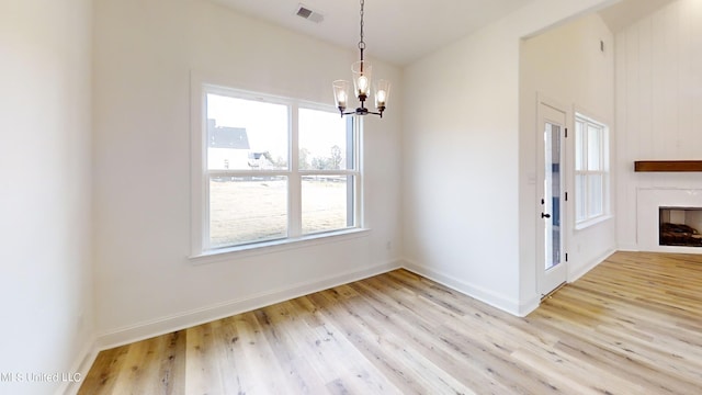 unfurnished dining area with an inviting chandelier, light hardwood / wood-style flooring, and a healthy amount of sunlight