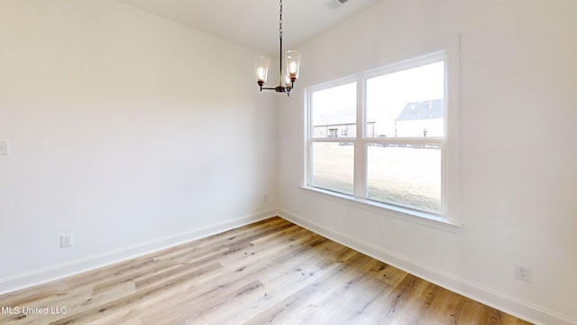 unfurnished room with a chandelier and light wood-type flooring