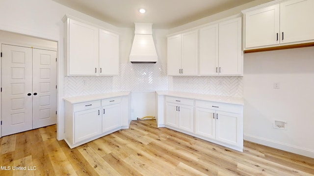 kitchen with white cabinetry, tasteful backsplash, and light hardwood / wood-style flooring