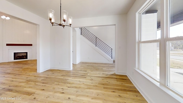 unfurnished dining area featuring light hardwood / wood-style flooring and a notable chandelier