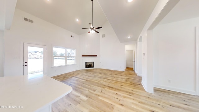 unfurnished living room with ceiling fan, high vaulted ceiling, and light wood-type flooring