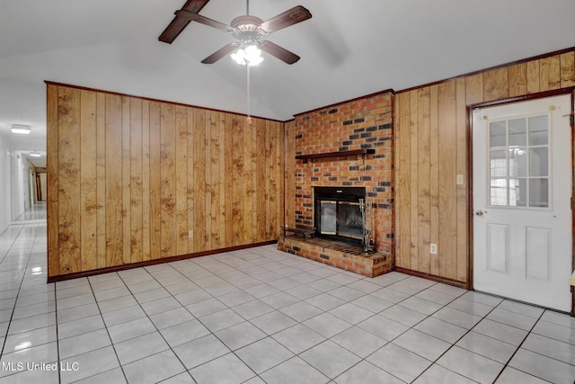 unfurnished living room featuring lofted ceiling with beams, a brick fireplace, ceiling fan, and wooden walls