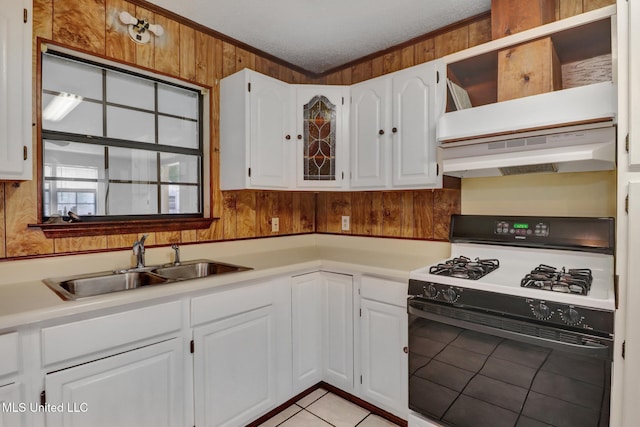 kitchen with gas range, a sink, light tile patterned floors, white cabinets, and ornamental molding
