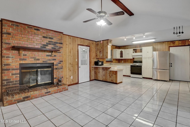 kitchen featuring light countertops, wood walls, freestanding refrigerator, a peninsula, and white gas stove
