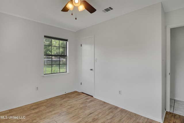 empty room featuring ceiling fan, visible vents, baseboards, and light wood finished floors