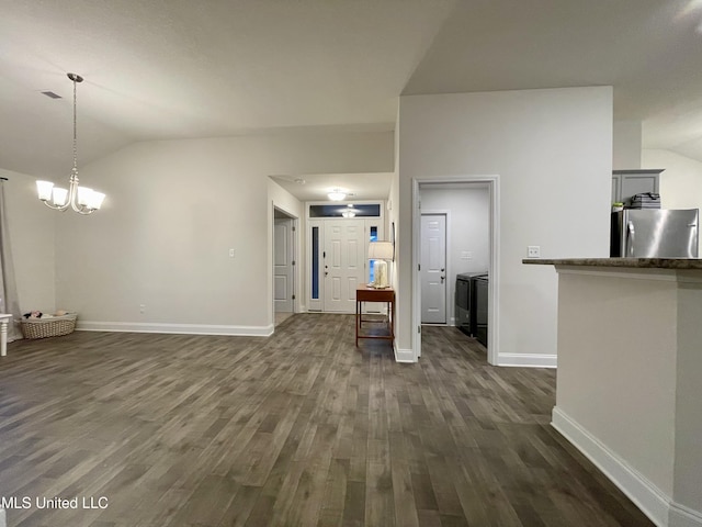 unfurnished living room featuring a notable chandelier, dark hardwood / wood-style flooring, lofted ceiling, and washing machine and clothes dryer