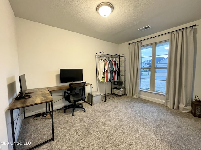 carpeted office space featuring a textured ceiling