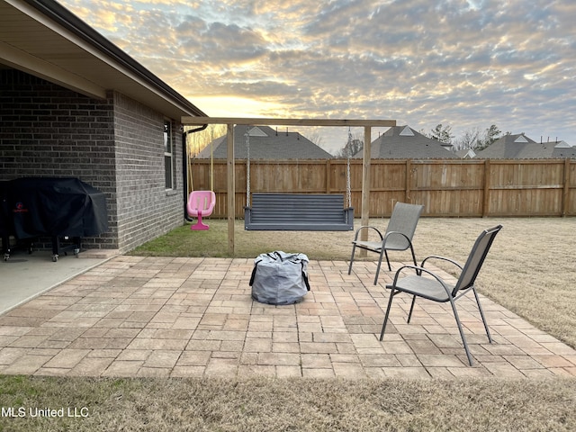 patio terrace at dusk featuring a grill