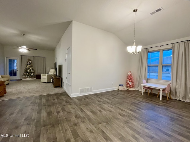 unfurnished dining area featuring ceiling fan with notable chandelier, dark wood-type flooring, and vaulted ceiling