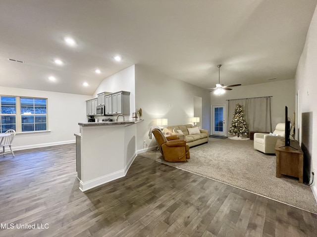 living room with lofted ceiling, ceiling fan, and dark wood-type flooring