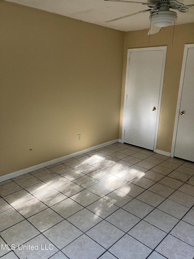 unfurnished room featuring ceiling fan, light tile patterned floors, and baseboards